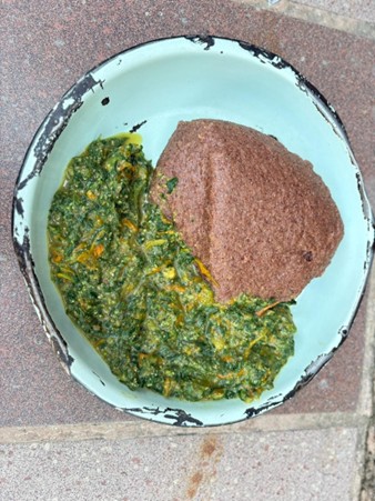 A blue bowl holding dark green and yellow substance and a dark colored circle.